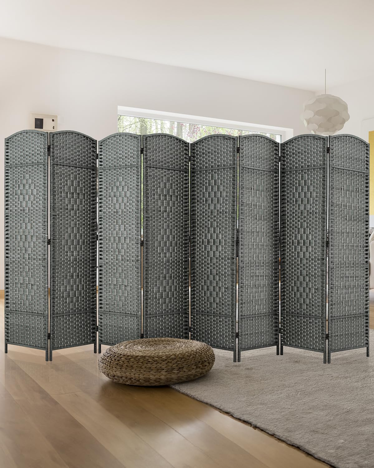 A sleek 8-panel grey bamboo room divider with a woven design stands behind a modern bed, offering privacy and style in a bright, minimalistic bedroom.
